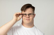 © Atlas - A smiling young man with cerebral palsy in glasses and a white T-shirt poses for the camera. World Genetic Diseases Day concept