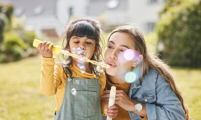 mother and girl child blowing bubbles together on grass in nature for picnic, happiness and love. su