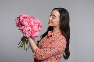 Canvas Print - Beautiful young woman with bouquet of peonies on light grey background