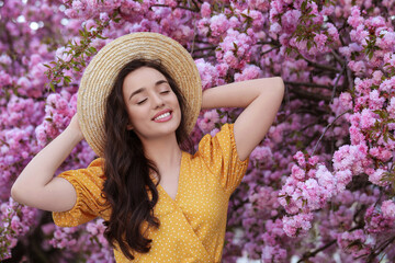 Wall Mural - Beautiful woman near blossoming sakura tree on spring day