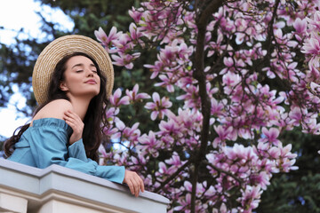 Poster - Beautiful woman near blossoming magnolia tree on spring day