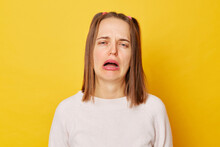 Displeased upset teenage girl in jumper with ponytails isolated over yellow background being discontent and unhappy as can`t achieve goals feels desperate has problems in life.