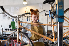Young Adult Female Repairing A Bicycle In A Bike Store