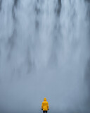 Mężczyzna stoi na tle wodospadu Skogafoss, Islandia