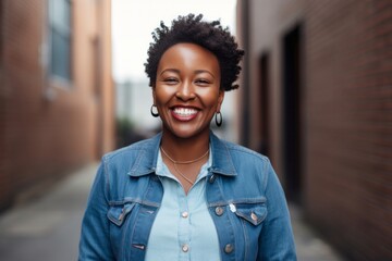 Wall Mural - Portrait of a happy Kenyan woman in her 30s wearing a denim jacket against a minimalist or empty room background