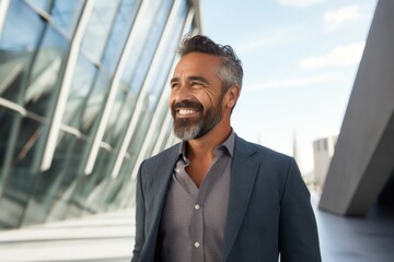 Portrait of a Mexican man in his 40s wearing a chic cardigan against a modern architectural background