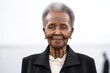 medium shot portrait of a confident Kenyan woman in her 70s wearing a sleek suit against a white background