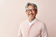 Portrait of a confident Japanese man in his 50s wearing a chic cardigan against a pastel or soft colors background