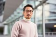 © Leon Waltz - medium shot portrait of a serious, Japanese man in his 30s wearing a cozy sweater against a modern architectural background