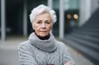 medium shot portrait of a serious, Polish woman in her 90s wearing a cozy sweater against a modern architectural background