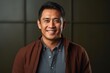 portrait of a happy Filipino man in his 40s wearing a chic cardigan against an abstract background