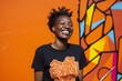 © Anne-Marie Albrecht - medium shot portrait of a happy Kenyan woman in her 30s wearing a fun graphic tee against an abstract background