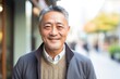 © Leon Waltz - portrait of a happy Japanese man in his 50s wearing a chic cardigan against a white background