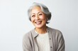 medium shot portrait of a Japanese woman in her 60s wearing a chic cardigan against a white background