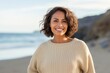 © Leon Waltz - portrait of a Mexican woman in her 40s wearing a cozy sweater against a beach background