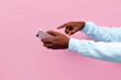 © Богдан Маліцький - african american male hands hold smartphone and choose point finger at the screen on pink isolated background