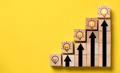 Fototapete - Glowing lightbulb on the top of up arrow and wooden block cube for human development of problem solving solution and creative thinking idea innovation concept.