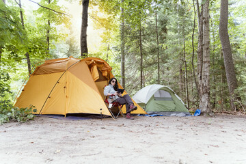 woman enjoying a moment alone in a campground reading her electronic device