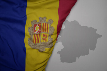 big waving national colorful flag and map of andorra on the gray background.