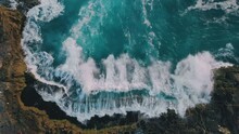 Top Down Aerial View From Above Of Giant Ocean Waves Crashing And Foaming On Empty Sand Tropical Beach With Big Rock Stones. Bird's Eye Aerial Shot Of Golden Beach Meeting Deep Blue Ocean Water.