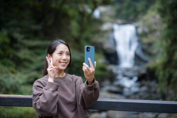 Wall Mural - Woman take selfie on cellphone with waterfall at hiking trail