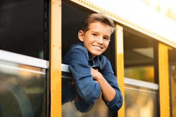 Handsome preteen boy looking out of school bus window