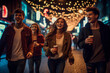 Four smiling friends cheering with hot drinks on a New Years night, enjoying and laughing togetherness on the street.