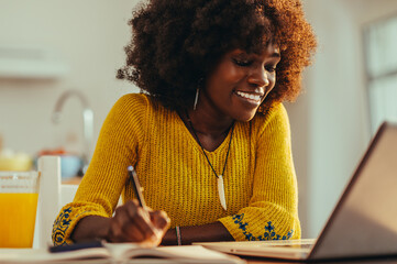 A cheerful african american adult student is following an online lecture