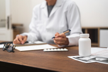 Poster - female doctor close-up medication prescription at table with ultrasound images, jar of pills. documenting medical details. 
