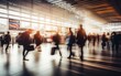 © piai - A bustling airport terminal scene with blurred travellers with baggage in motion. Generative AI