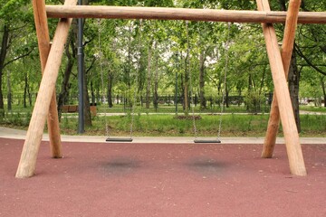 Wall Mural - Wooden playground made of natural eco-friendly material in public city park. Modern safety children outdoor equipment. Concept of sustainable lifestyle and ecology. Children rest and games on open air