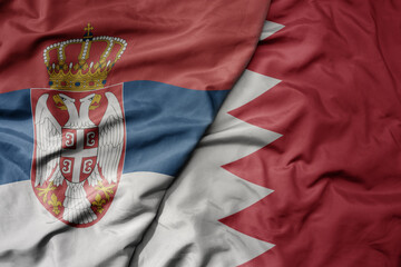 big waving national colorful flag of serbia and national flag of bahrain .