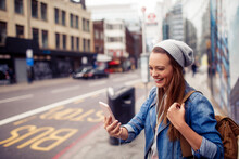 Young Caucasian woman using a smartphone while commuting on the streets of London UK