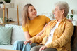 © Pixel-Shot - Young woman with her grandmother sitting on sofa at home