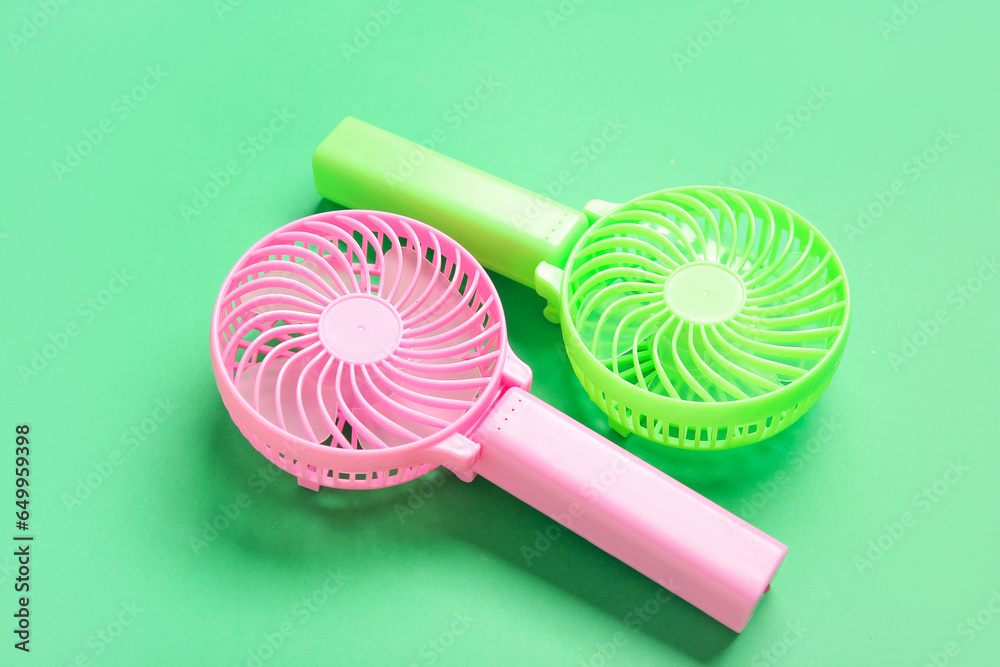 Different manual fans on green background, closeup