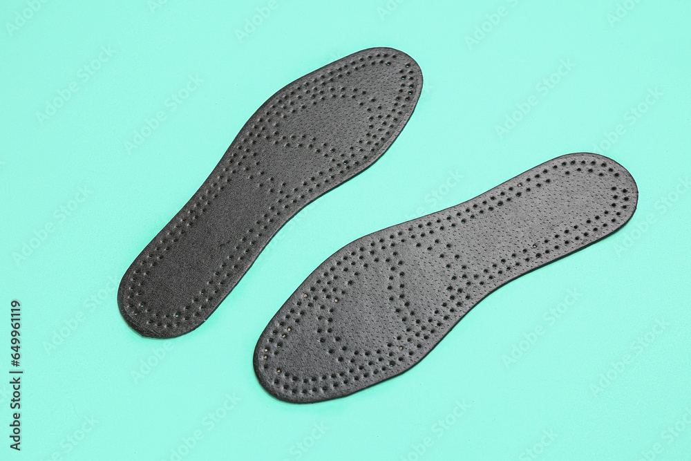 Pair of black orthopedic insoles on color background