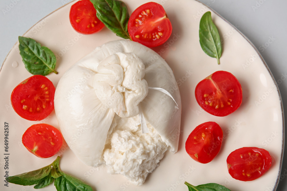 Plate with tasty Burrata cheese on grey background