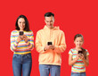 Leinwandbild Motiv Happy family using mobile phones on red background