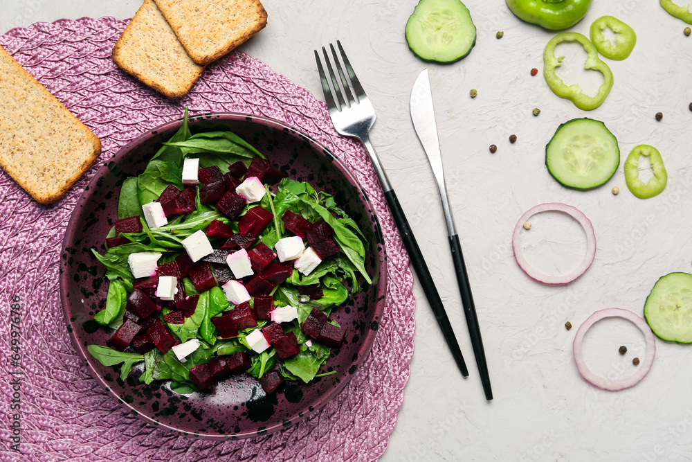 Bowl of fresh vegetable salad with beet, crackers and ingredients on white background
