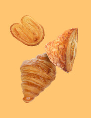 Wall Mural - Aromatic fresh pastries falling on pale orange background