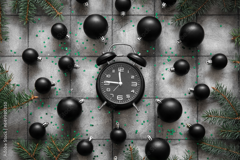 Composition with alarm clock, Christmas balls and fir branches on grunge tile background