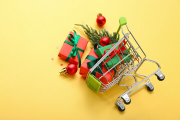 Small shopping cart with Christmas decor on orange background