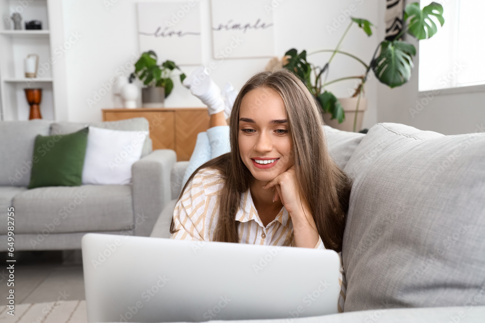 Young woman using laptop on couch in living room