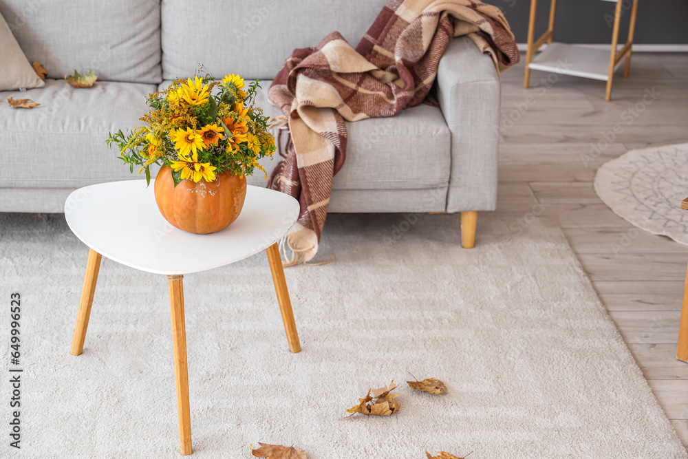 Pumpkin with autumn bouquet on table in living room