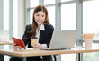 © Bangkok Click Studio - Portrait shot of Asian professional successful female businesswoman secretary employee in formal suit sitting smiling look at camera taking break drink coffee browsing tablet online in company office