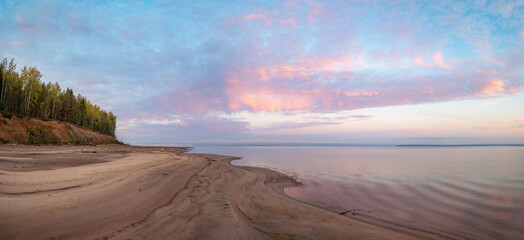 Wall Mural - Pink dawn on the sandy bank of the Kama River, clouds in the distance fog, reflection in the water.