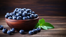 Fresh blueberries in a bowl on wooden background.