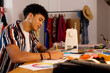 © Wavebreak Media - Focused biracial male fashion designer sketching designs and sitting at desk in studio