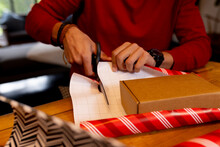 Biracial Man Cutting Wrap For Christmas Presents At Home