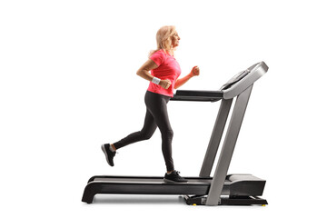 Sticker - Full length profile shot of a mature woman running on a treadmill